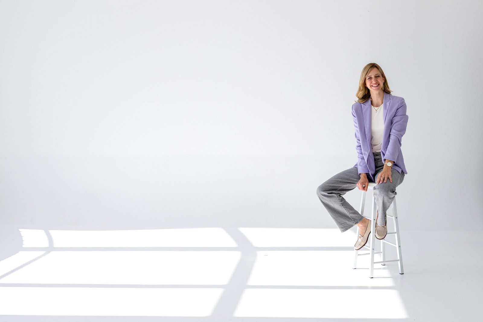 Madleen Frommholz sitzt im Business-Outfit auf einem Barhocker im modernen Büro beim Start in die Selbstständigkeit als Mutter